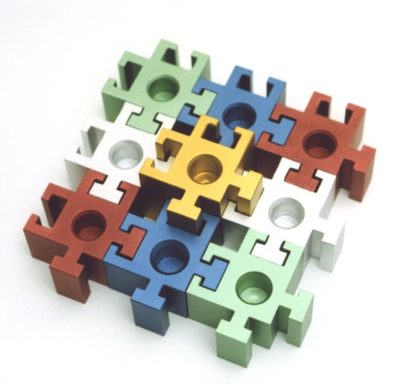 Anyone with a stitch of playfulness won't be able to keep their hands off this classically detailed anodized aluminum puzzle piece menorah. Either link the square jigsaw puzzle pieces together to form a kosher chanukiyah, or spend some time figuring out how to get the puzzle back into its original square form. It's not as easy as it looks! The shammash piece is twice the height of the rest of the links. Available in your choice of color combination. Wooden travel/storage box included.